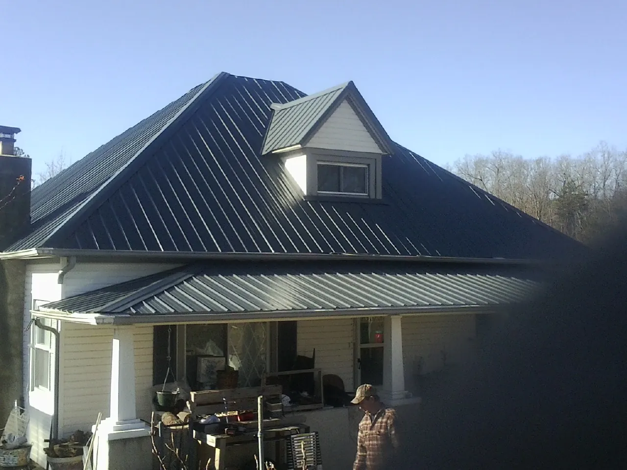Dark blue standing seam metal roof with a dormer above a front porch in Baldwin