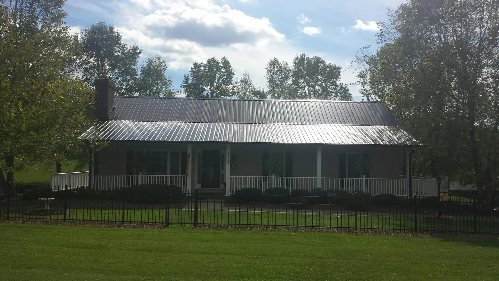Gray metal roof on a brick ranch with a full width front porch — Gutter Guard Installation work by our crew in Baldwin